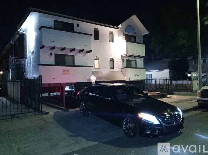 A black car is parked in front of a white building at night.