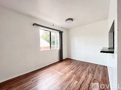 A room with wooden flooring and a sliding glass door.
