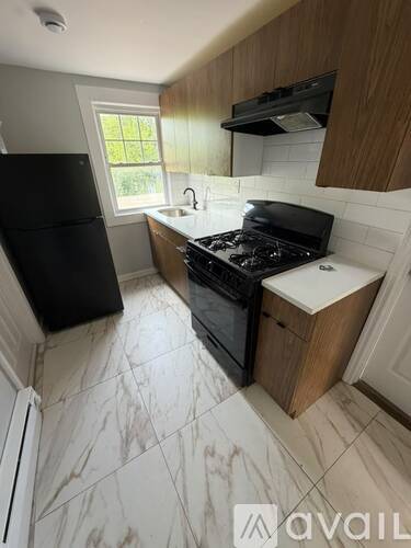 A kitchen with a black fridge, black stove, and wooden cabinets.