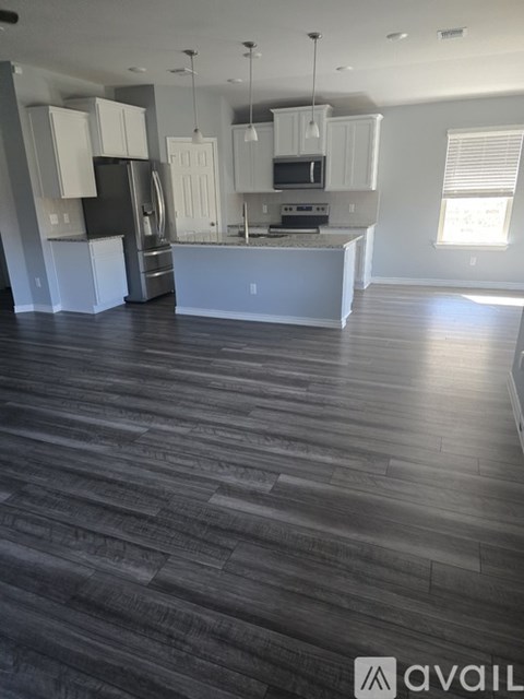 A kitchen with white cabinets and a wooden floor.