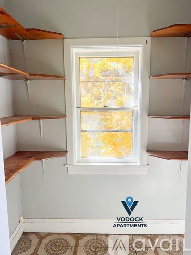 A Vodock Apartments sign is on a wall above a window with a view of trees outside.