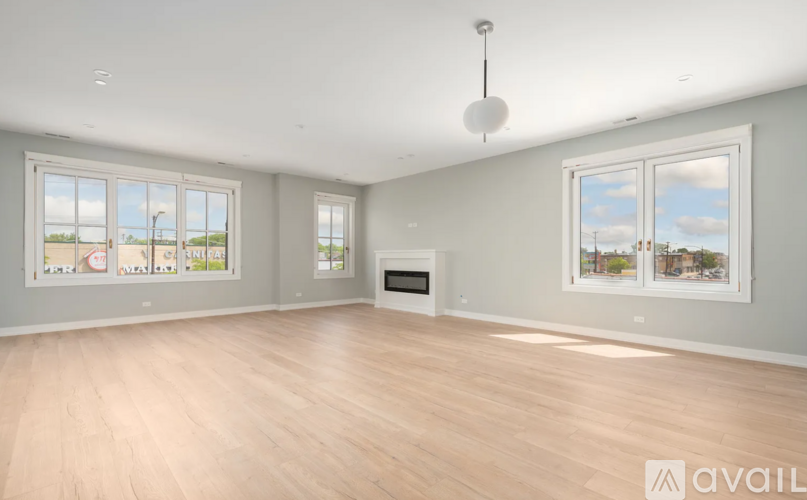 A spacious room with wooden floors and large windows.