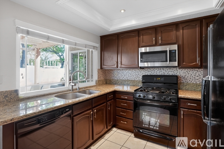 A kitchen with brown cabinets and black appliances.