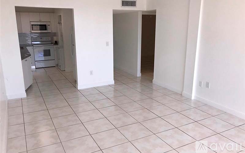 A kitchen with white cabinets and appliances is visible through a doorway.
