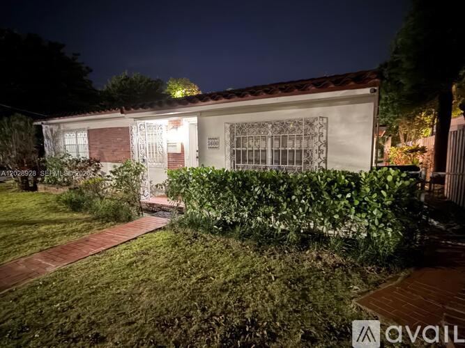 A house with a well-maintained lawn and a brick pathway leading to the front door.