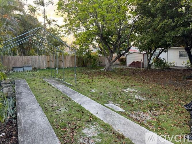 A backyard with a concrete walkway and a fence.