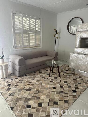 A living room with a couch, a plant, and a mirror on the wall.