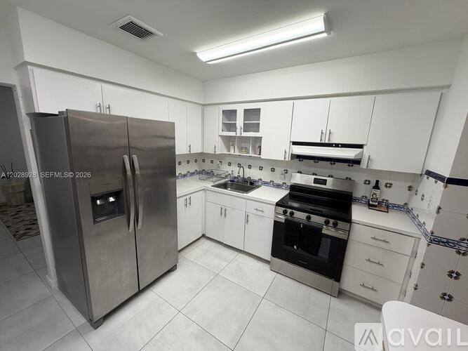 A modern kitchen with a stainless steel refrigerator and white cabinets.