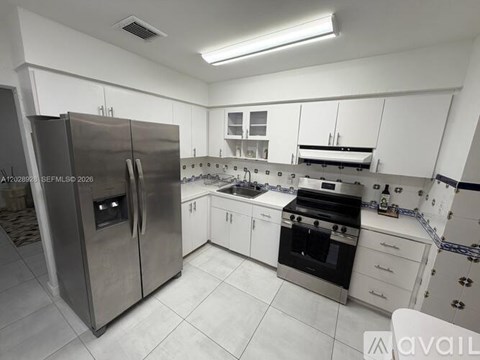 A modern kitchen with a stainless steel refrigerator and white cabinets.
