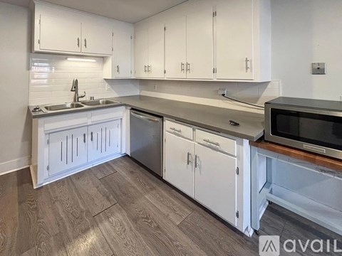 A kitchen with white cabinets and a wooden floor.