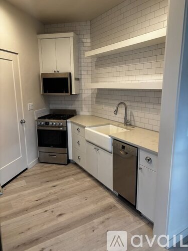 A kitchen with white cabinets and a brick wall backsplash.