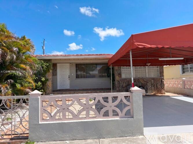 A house with a red awning and a white fence.