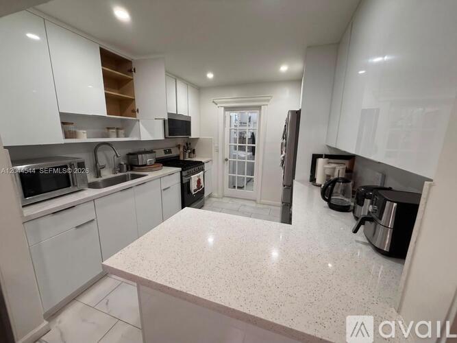 A kitchen with white cabinets and a marble countertop.