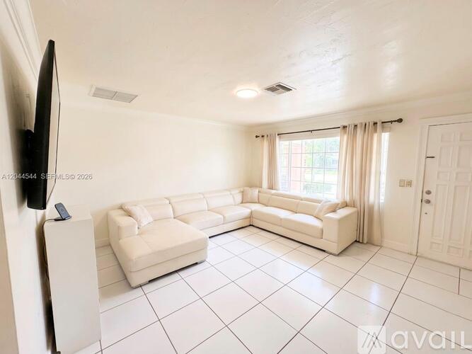 A living room with a white sofa and television.