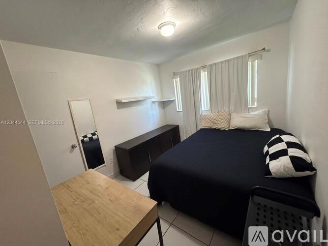 A bedroom with a bed, nightstand, and a small table.