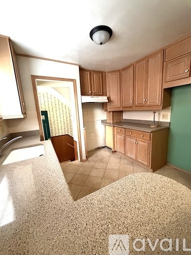 A kitchen with wooden cabinets and a tiled floor.