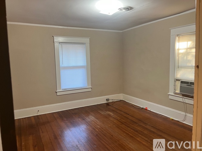 A room with wooden floors and a window with blinds.