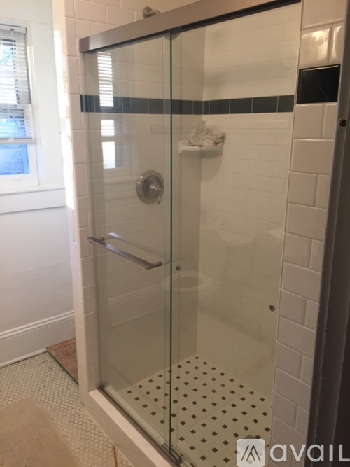 A shower with a glass door and a tiled floor.