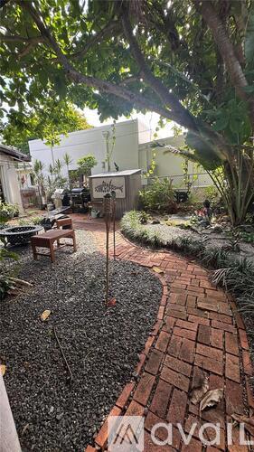 A garden with a brick pathway and a white building in the background.