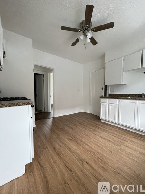 A room with a ceiling fan and wooden flooring.