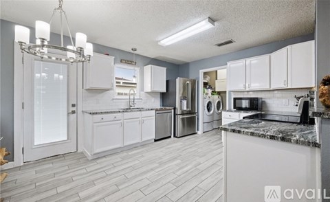 A kitchen with white cabinets and a marble countertop.