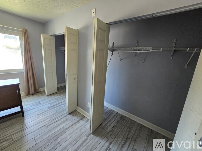 A room with a grey wall and a wooden floor with a white door.