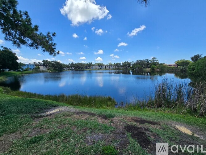 A serene landscape with a lake, trees, and a clear sky.