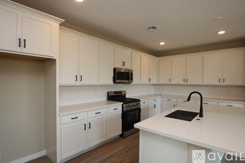 A kitchen with white cabinets and a black stove top oven.