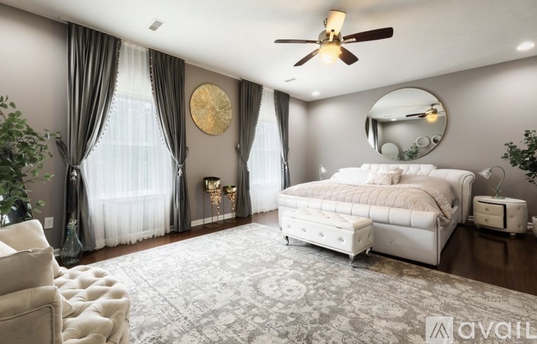 A bedroom with a large bed, a ceiling fan, and a mirror on the wall.