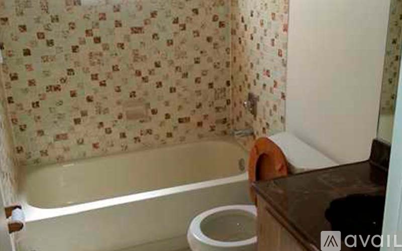 A bathroom with a toilet and a bathtub with a floral shower curtain.