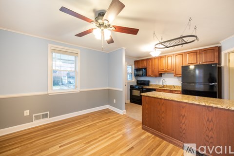 A kitchen with wooden cabinets and a black fridge.