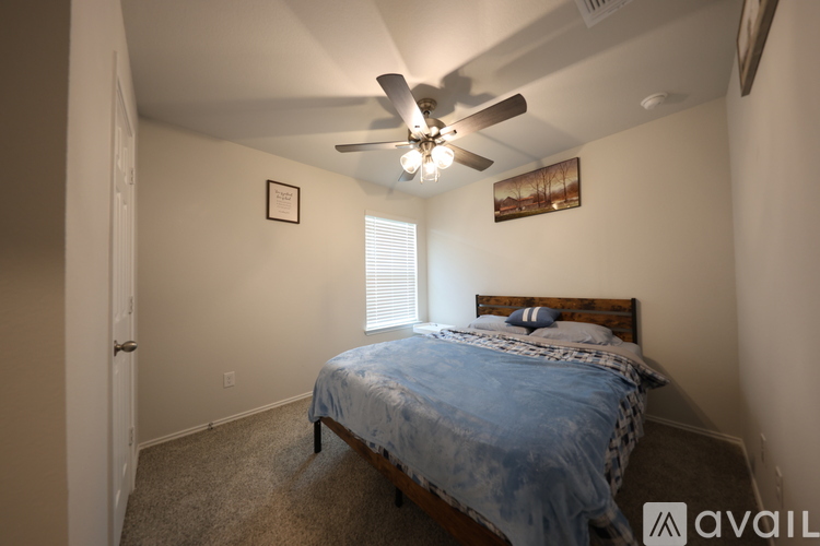 A bedroom with a bed, ceiling fan, and two pictures on the wall.