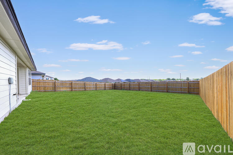 A backyard with a wooden fence and a grassy area.