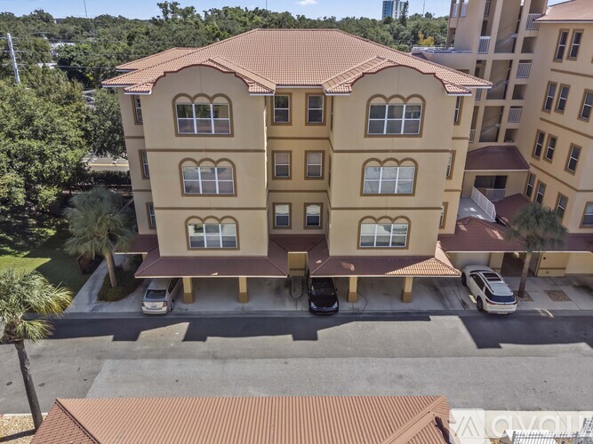 A large building with a red roof and a parking lot in front.