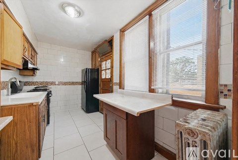 A kitchen with wooden cabinets and a black refrigerator.