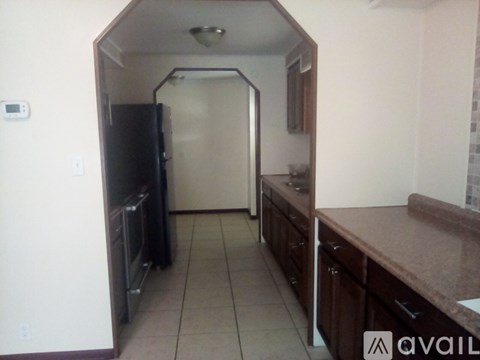 A kitchen with a black refrigerator and brown countertops.