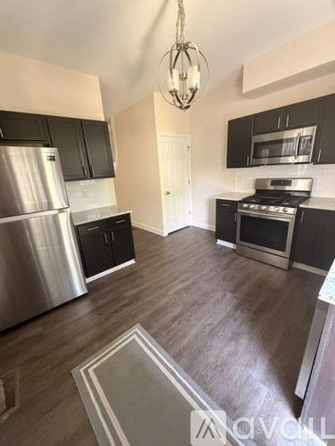 A kitchen with a stainless steel refrigerator and black cabinets.