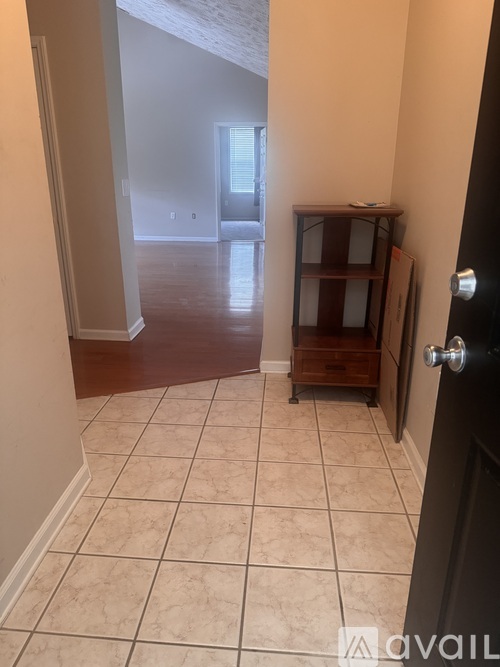 A hallway with a black door and a wooden cabinet.
