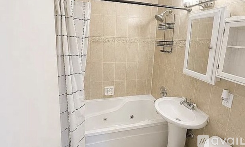 A bathroom with a white tub, sink, and shower curtain.
