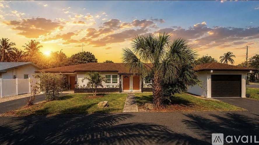 A house with a driveway and palm trees in front of it.