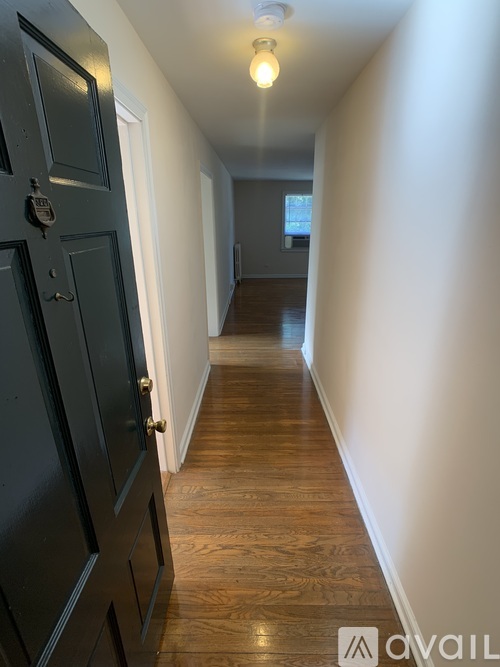 A long hallway with a black door on the left.
