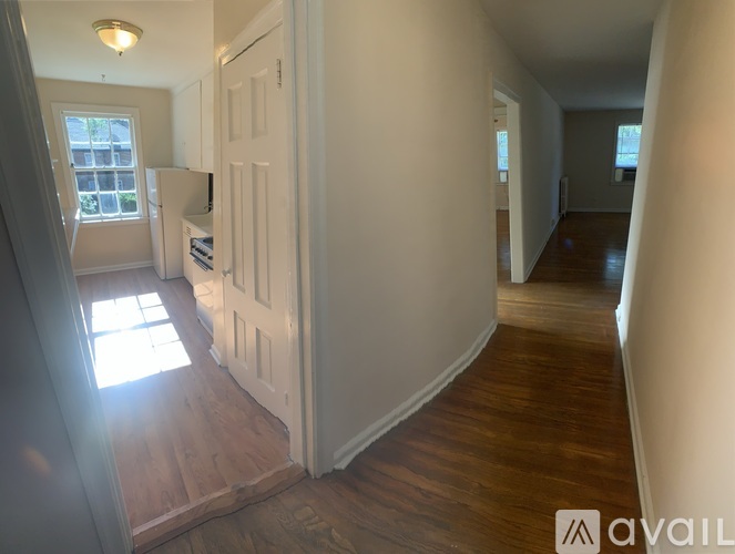 A hallway with a white door and wooden floors.