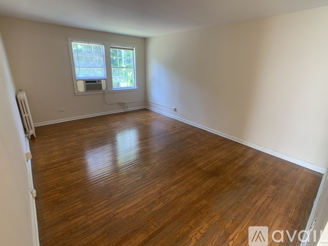 A room with wooden flooring and a window with blinds.
