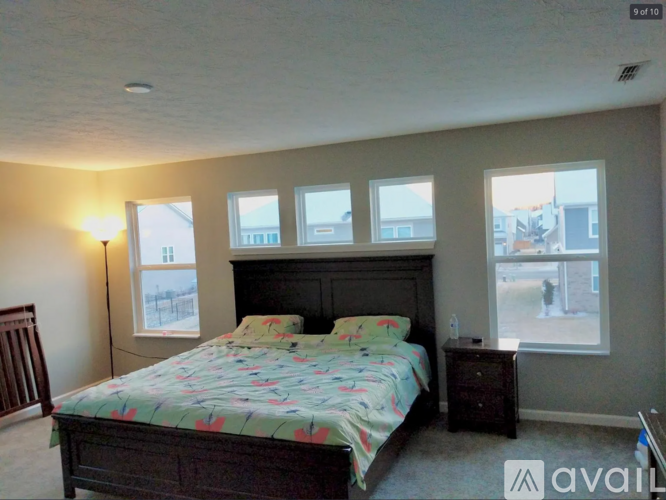 A bedroom with a large bed and four windows.