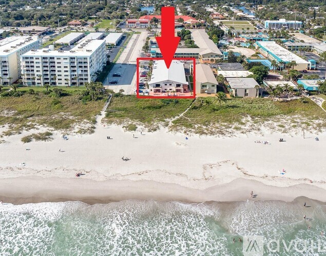 A beachfront property is highlighted with a red arrow in an aerial view.