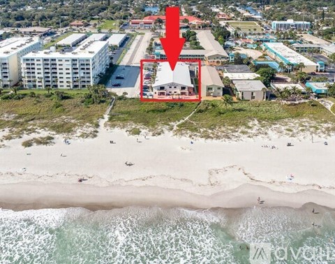 A beachfront property is highlighted with a red arrow in an aerial view.