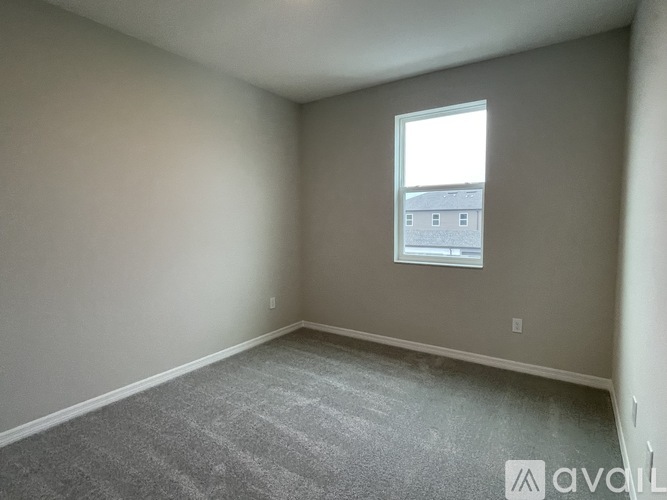 A room with a carpeted floor and a window showing a building outside.