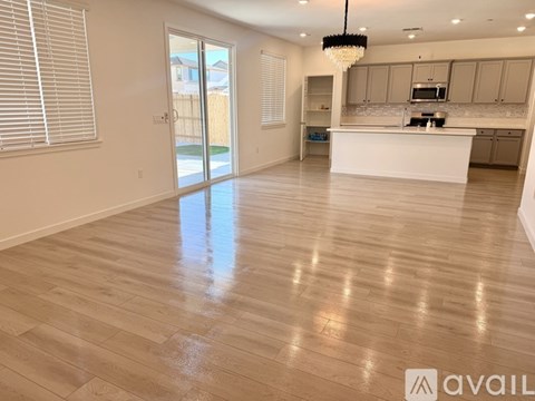 A spacious kitchen and living room with wooden flooring and a chandelier.