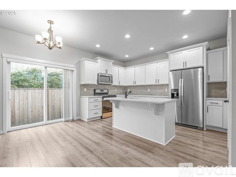 A well-lit kitchen with white cabinets and a wooden floor.