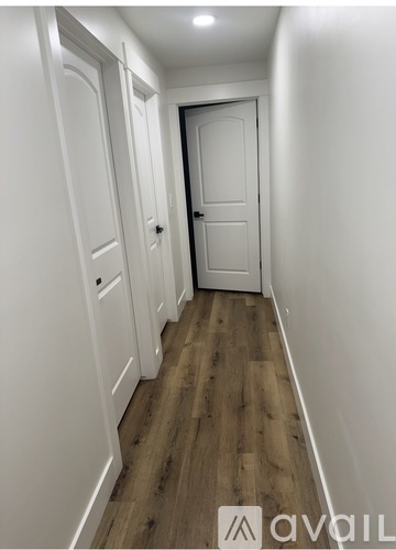 A hallway with white doors and wooden floors.